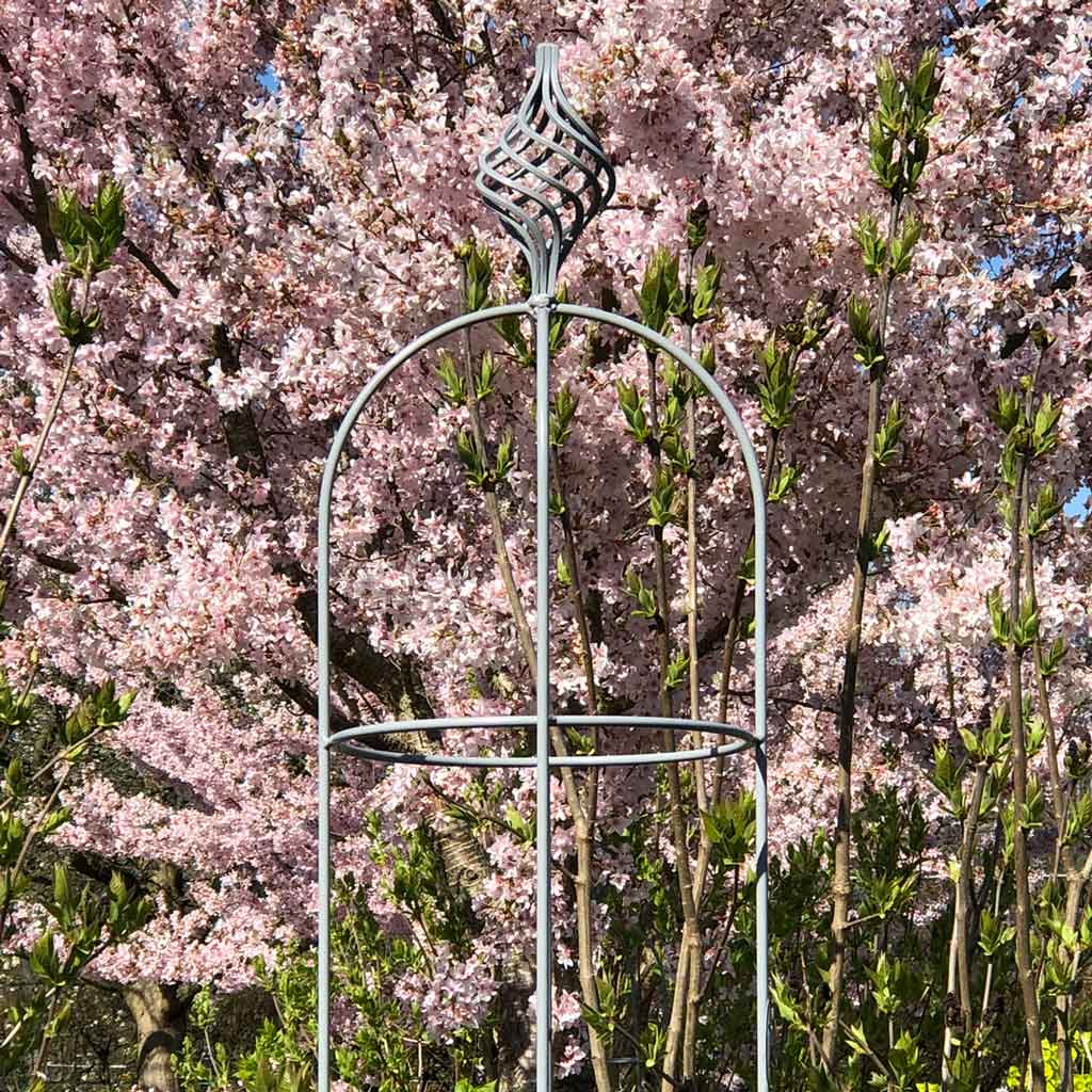 Bluebell Elegance Obelisk with pink flowers in the background